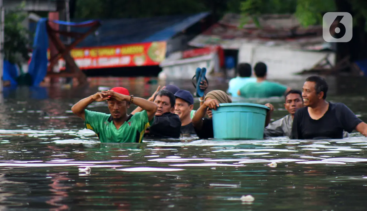 Warga melintasi banjir yang merendam perumahan Villa Mutiara Pluit, Tangerang, Banten, Senin (3/2/2020). Banjir disebabkan jebolnya tanggul sungai di sekitar kawasan tersebut. (merdeka.com/Magang/Muhammad Fayyadh)