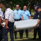 Polisi mengangkat puing pesawat yang diduga milik MH370 untuk diamankan di pantai Saint - Andre, Perancis, Rabu (29/30/2015). Puing tersebut ditemukan oleh orang-orang yang sedang membersihkan pantai. (REUTERS/Prisca Bigot)