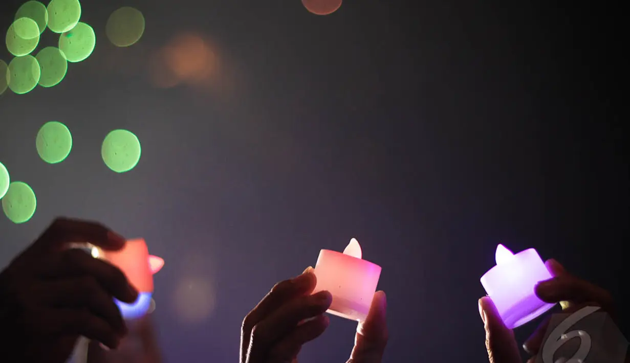 Beberapa orang tampak memegang lilin di kawasan Monas, Jakarta, Rabu (31/12) dini hari. (Liputan6.com/Faizal Fanani)