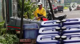 Pedagang tengah mengisi air  bersih ke dalam drigen untuk dijual di Kembangan, Jakarta, Rabu (13/7/2022). Air bersih yang dijual seharga 5 ribu per drigen tersebut untuk memenuhi kebutuhan air bersih bagi warga sekitar kawasan tersebut. (Liputan6.com/Angga Yuniar)