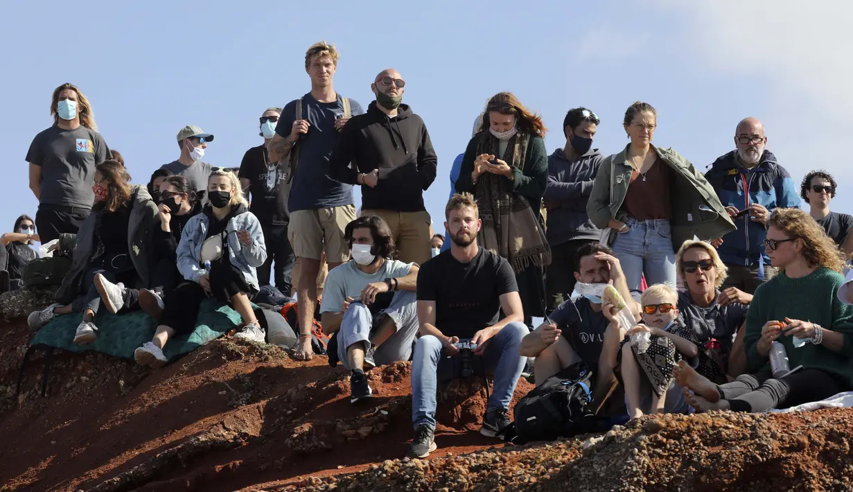 Orang-orang berkumpul di sepanjang puncak tebing untuk menyaksikan sesi selancar derek di Praia do Norte atau Pantai Utara di Nazare, Portugal, Kamis (29/10/2020). (AP Photo/Pedro Rocha)