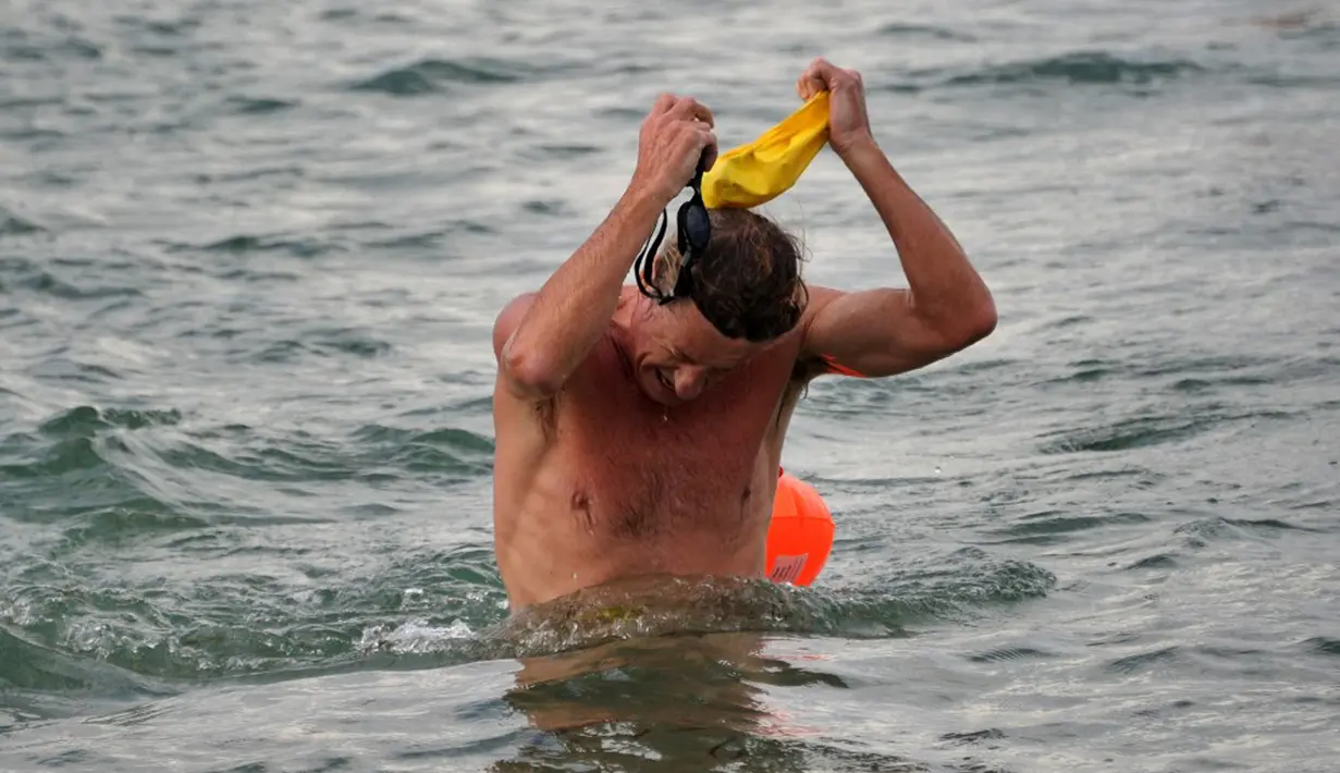 Seorang peserta mencapai garis finish dalam kompetisi renang Oceanman Bali 2021 di sebuah pantai di Sanur, Denpasar, Bali, Sabtu (18/9/2021). Oceanman Bali 2021 mempertandingkan empat kategori yaitu OceanKids, Sprint, Half Oceanmen, dan Oceanman. (SONY TUMBELAKA/AFP)