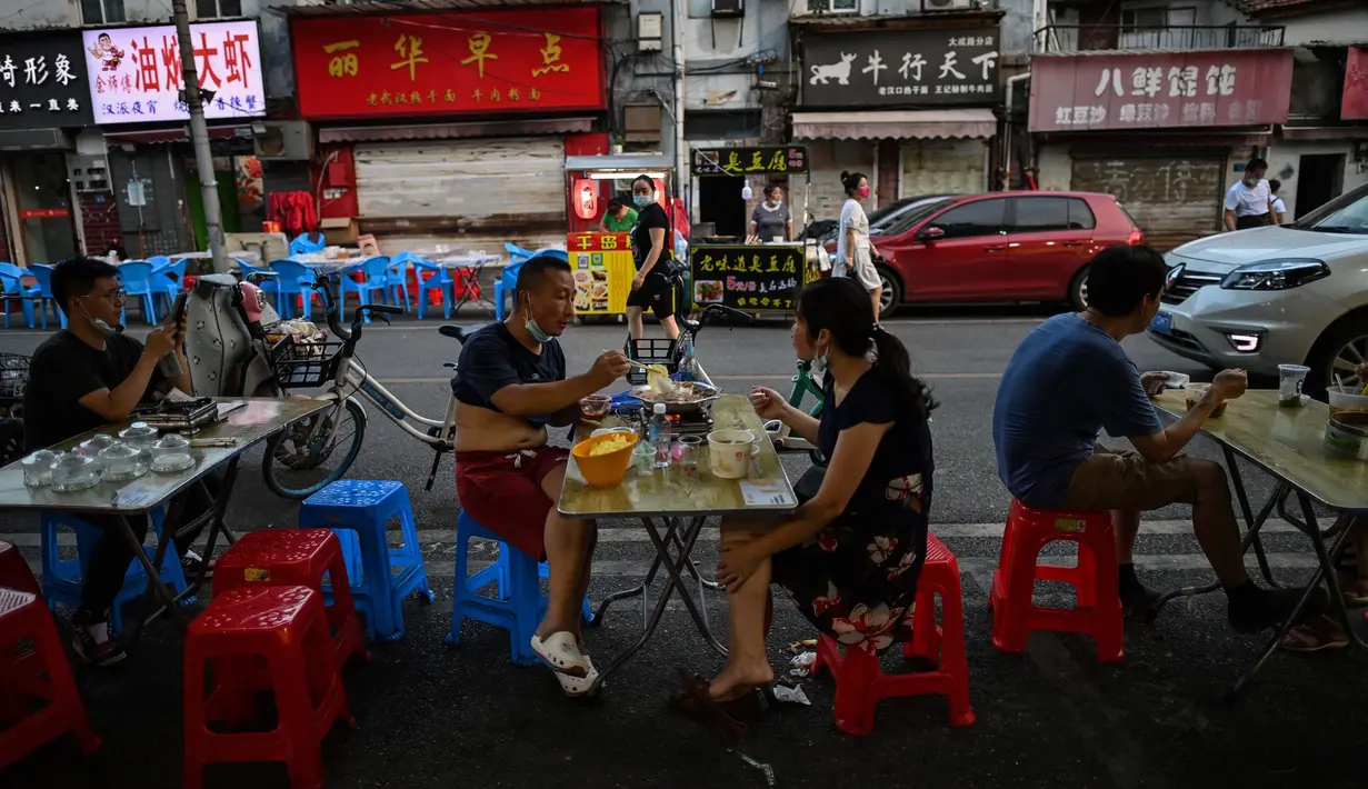Pasangan sedang makan pada sore hari di depan sebuah restoran kecil di Wuhan, Provinsi Hubei, China, 4 Agustus 2020. Antrean panjang pelanggan sekarang terbentang di luar kios sarapan, jauh dari ketakutan akan kerumunan seperti awal pandemi COVID-19. (Hector Retamal/AFP)