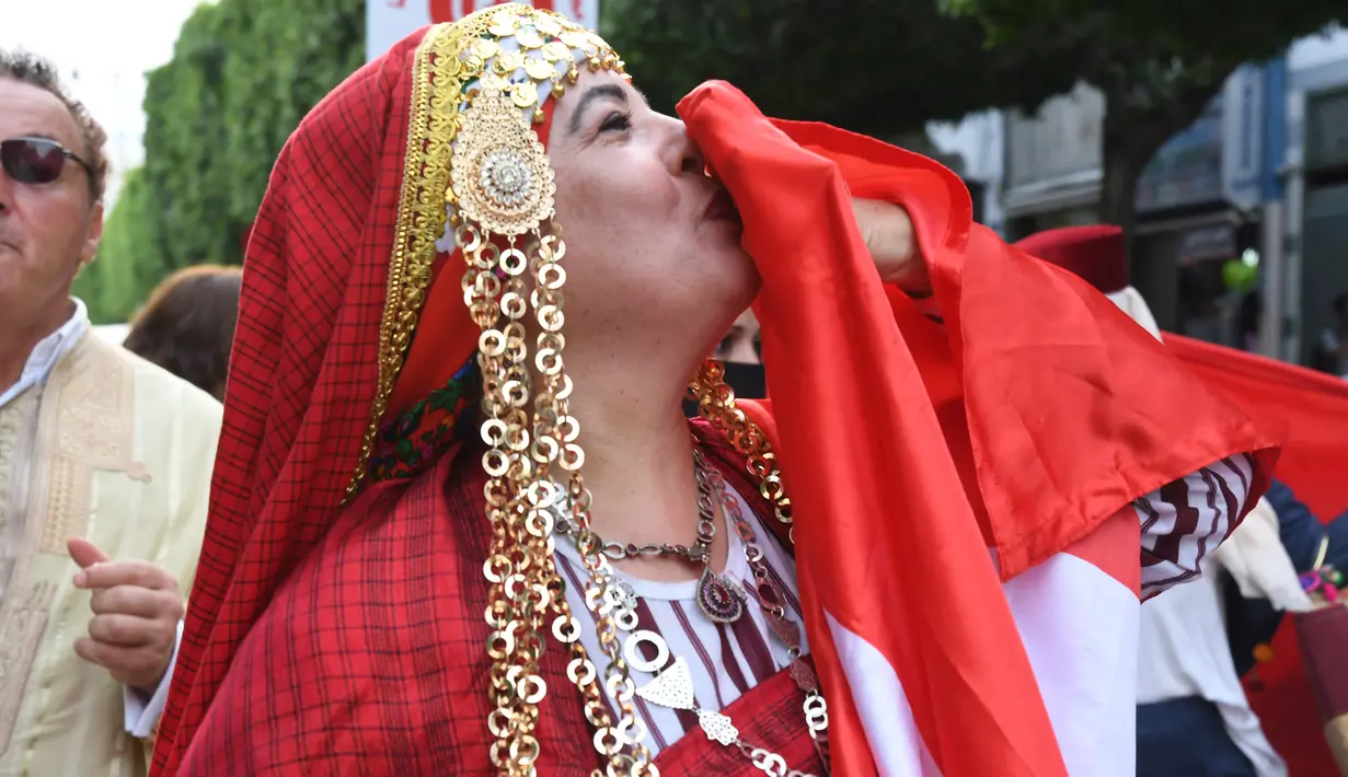 Seorang perempuan yang mengenakan kostum tradisional mencium bendera nasional Tunisia dalam perayaan tahunan Hari Perempuan Nasional di pusat kota Tunis, Tunisia, pada 13 Agustus 2020. (Xinhua/Adel Ezzine)