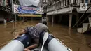 Warga mengambil barang dari air saat banjir melanda Jalan Bina Warga Rt 005/Rw 07 Kelurahan Rawa Jati, Jakarta, Senin (8/2/2021). Banjir setinggi 60-190 cm tersebut disebabkan oleh luapan air Sungai Ciliwung dan curah hujan Jakarta yang tinggi. (Liputan6.com/Johan Tallo)