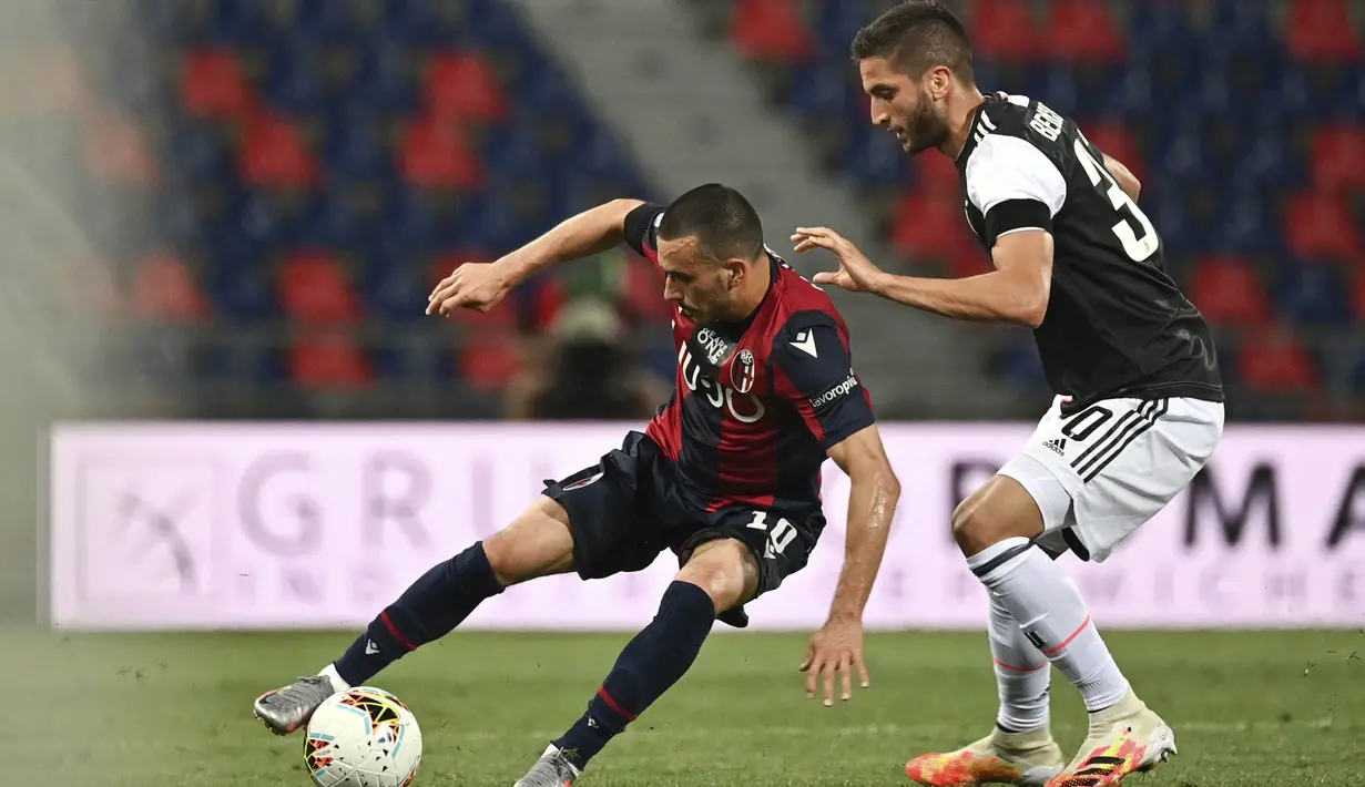Pemain Juventus, Rodrigo Bentancur, berebut bola dengan pemain Bologna, Nicola Sansone, pada laga Serie A di Stadion Renato Dall'Ara, Senin (22/6/2020). Juventus menang 2-0 atas Bologna. (AP/Massimo Paolone)
