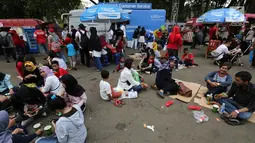 Pengunjung menikmati makan sambil lesehan jelang Closing Ceremony Asian Games 2018 di kawasan Gelora Bung Karno, Jakarta, Minggu (2/9). Kursi yang penuh menyebabkan mereka duduk lesehan. (Liputan6.com/Fery Pradolo)