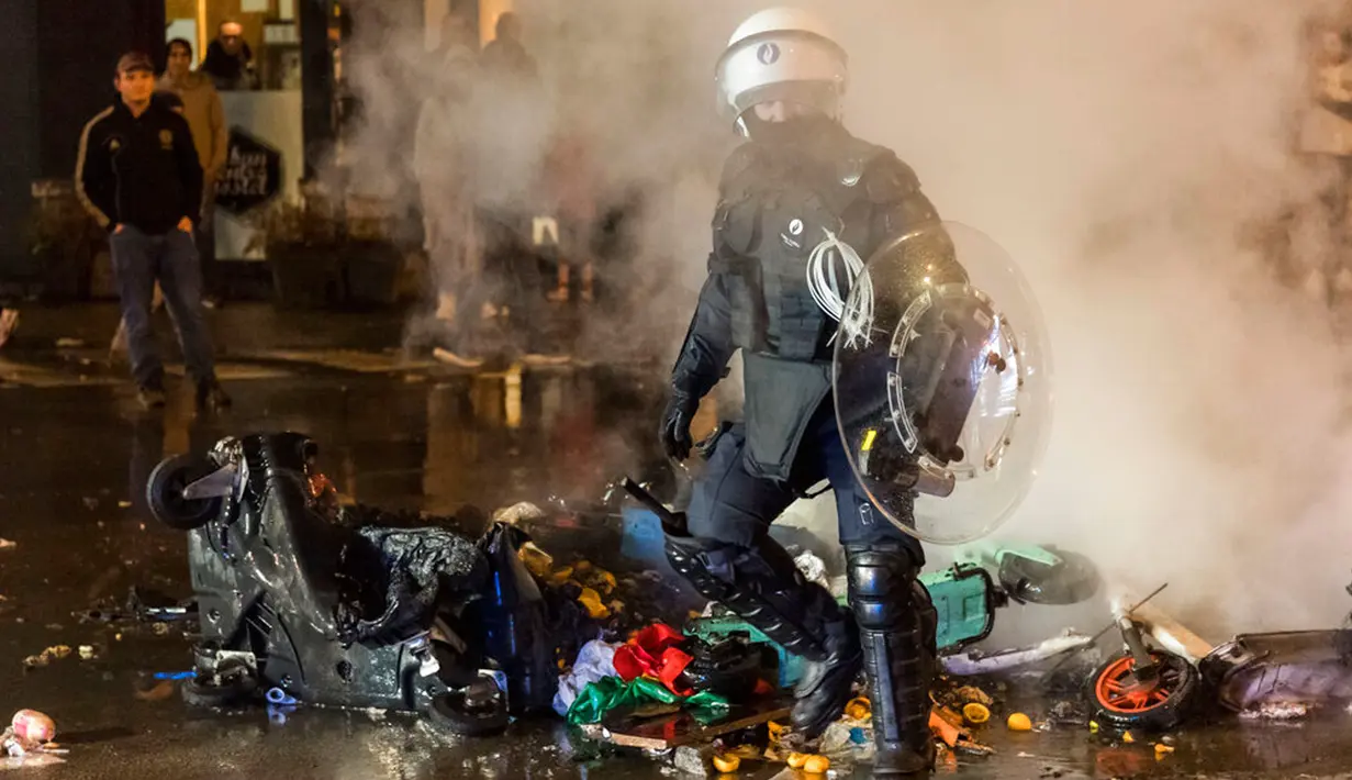 Seorang polisi antihuru-hara berjalan di jalan utama di Brussel, Belgia, 27 November 2022. Polisi harus menutup sebagian pusat Kota Brussel dan bergerak dengan meriam air serta gas air mata untuk membubarkan massa menyusul kerusuhan selama dan setelah Maroko menang 2-0 atas Belgia di Piala Dunia 2022. (AP Photo/Geert Vanden Wijngaert)