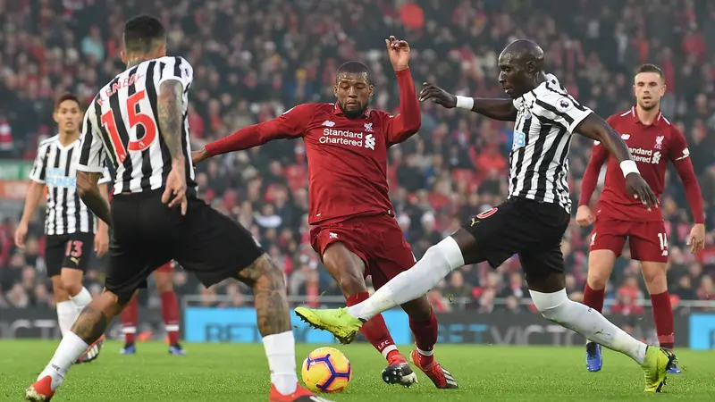 Gelandang Liverpool, Georginio Wijnaldum, berusaha melewati kepungan pemain Newcastle pada laga Premier League di Stadion Anfield, Liverpool, Rabu (26/12). Liverpool menang 4-0 atas Newcastle. (AFP/Paul Ellis)