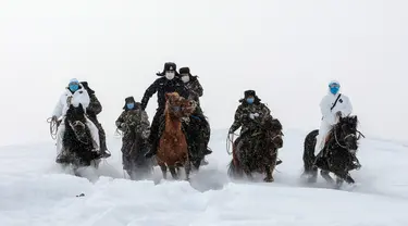 Petugas polisi mengenakan masker wajah berusaha melintasi jalanan bersalju saat akan melakukan sosialisasi tentang bahaya virus COVID-19 sekaligus memeriksa kondisi kesehatan warga daerah terpencil di Altay, Wilayah Xinjiang, China (19/2/2020). (AFP/STR)