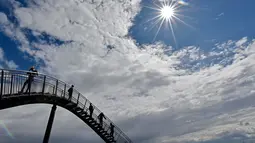 Orang-orang berjalan di sebuah instalasi tangga melingkar "Tiger and Turtle" di Duisburg, 30 April 2018. Jalan setapak menyerupai roller coaster dengan tinggi 21 meter ini dibangun oleh seniman Jerman, Heike Mutter dan Ulrich Genth. (AP/Martin Meissner)