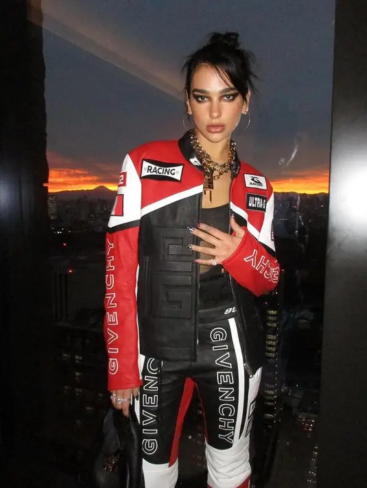 Mengenakan bodysuit hitam transparan, Dua Lipa melapisi outfitnya dengan two piece biker set berwarna merah, hitam, dan putih. [instagram/dualipa]