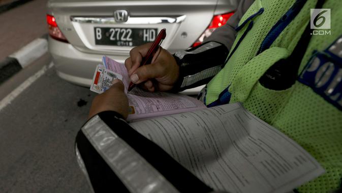 Polisi memberikan surat tilang kepada pengemudi mobil berpelat nomor genap di Jalan S Parman, Jakarta, Rabu (1/8). Polisi hari ini mulai memberlakukan sanksi tilang kepada pelanggar aturan di kawasan perluasan ganjil genap (Liputan6.com/Johan Tallo)