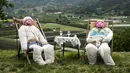 <p>Sebuah gambar pada 3 Mei 2022 menunjukkan dua orang-orangan sawah di ladang selama pekan raya tahunan di desa Castellar, Italia utara, dekat Cuneo. Warga menghias orang-orangan sawah layaknya manusia. Seperti mengenakan gaun, kemeja, topi, dan kaca mata lalu menempatkannya di kebun, halaman, ladang serta jalan.(MARCO BERTORELLO / AFP)</p>