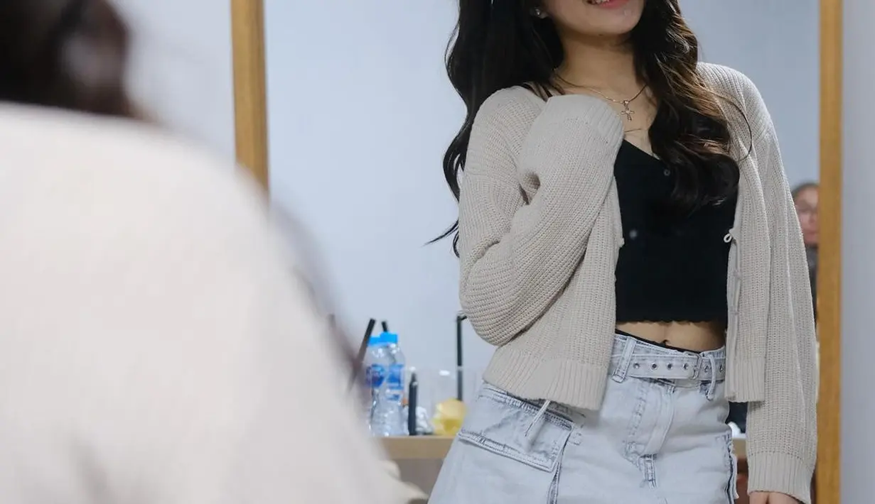 Gaya imut Eca Aura difoto di kaca. Ia mengenakan tank top hitam ditumpuknya dengan knitted outer cokelat, dipadu mini denim skirt. [Foto: Instagram/elsaajapasal]