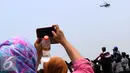 Warga mengabadikan helikopter saat gladi bersih HUT ke-70 TNI di Cilegon, Banten, Sabtu (3/10/2015). Jelang HUT ke-70 TNI tersebut menjadi daya tarik tersendiri bagi warga untuk menyaksikan secara dekat atraksi TNI. (Liputan6.com/Immanuel Antonius)