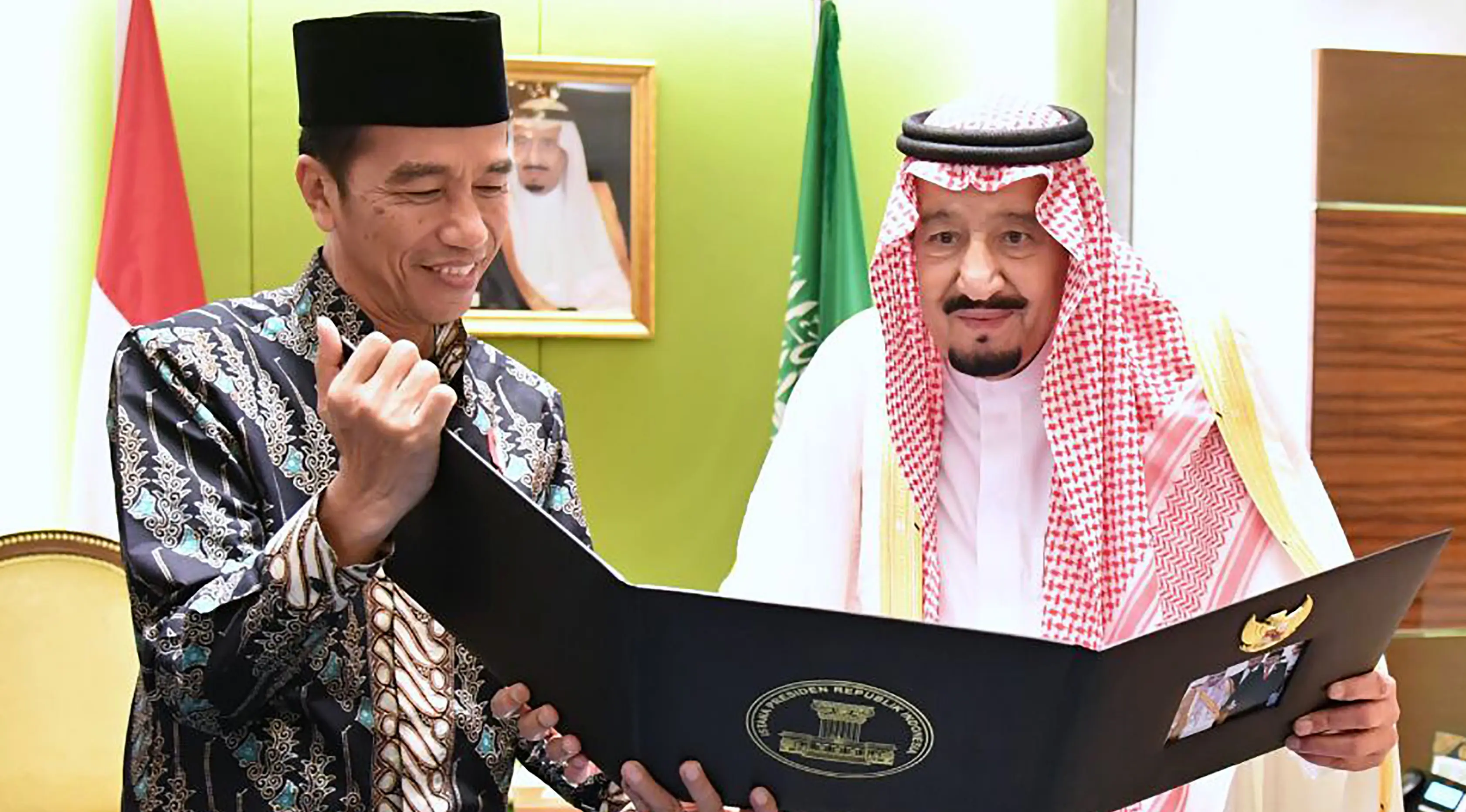 Presiden RI, Joko Widodo (Jokowi) memperlihatkan album foto dari pertemuan mereka di Bogor sehari sebelumnya untuk Raja Arab Saudi Salman bin Abdul Aziz di Jakarta, Kamis (2/3). (AFP PHOTO / PRESIDEN PALACE / Laily Rachev)