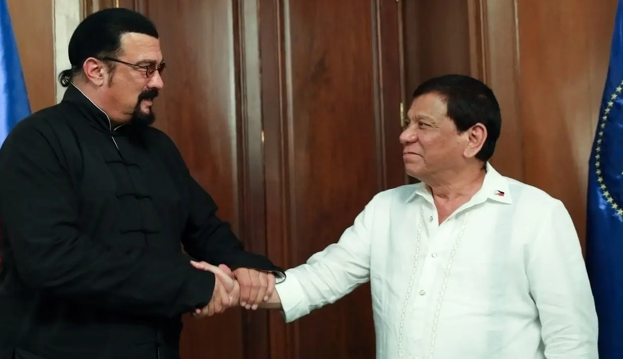 Presiden Filipina, Rodrigo Duterte (kanan) berjabat tangan dengan aktor laga Hollywood, Steven Seagal yang sedang melakukan kunjungan kehormatan di Istana Kepresidenan Malacanang di Manila, Kamis (12/10). (Handout/PPD/AFP)