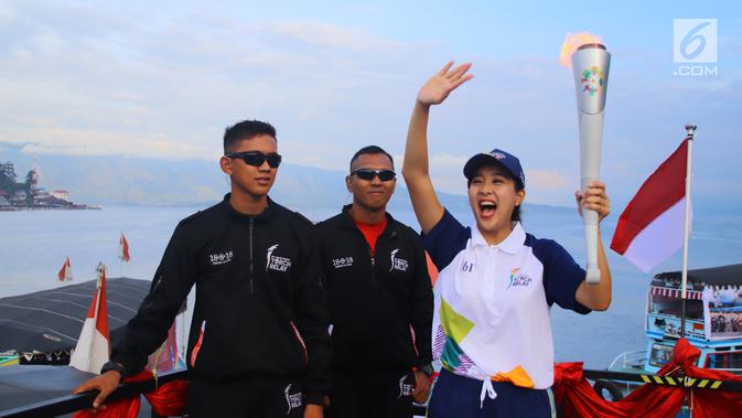 Artis Olivia Zalianty membawa obor Asian Games 2018 berkeliling Danau Toba di Sumatra Utara, Rabu (1/8). Obor Asian Games itu akan di bawa berlayar dengan kapal hias di Danau Toba dan bersepeda menuju pantai bebas Danau Toba. (Liputan6.com/Reza Perdana)