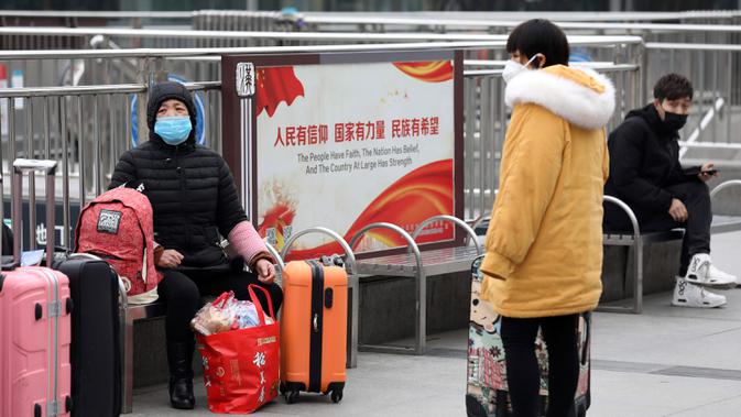 Para pelancong duduk dengan barang-barang mereka di luar Stasiun Kereta Api Hankou yang ditutup di Wuhan, Provinsi Hubei, China, Kamis (23/1/2020). Pemerintah China mengisolasi Kota Wuhan yang berpenduduk sekitar 11 juta jiwa untuk menahan penyebaran virus corona. (Chinatopix via AP)