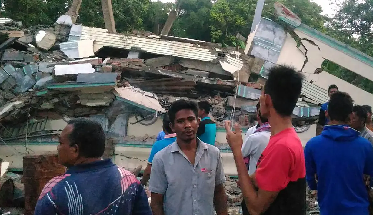 Warga mengamati sebuah bangunan yang roboh menyusul gempa 6,4 SR di Kabupaten Pidie Jaya, Aceh, Rabu (7/12). Sejumlah bangunan di Kabupaten Pidie Jaya rusak akibat gempa yang tak berpotensi tsunami tersebut. (Zian Muttaqien/AFP)