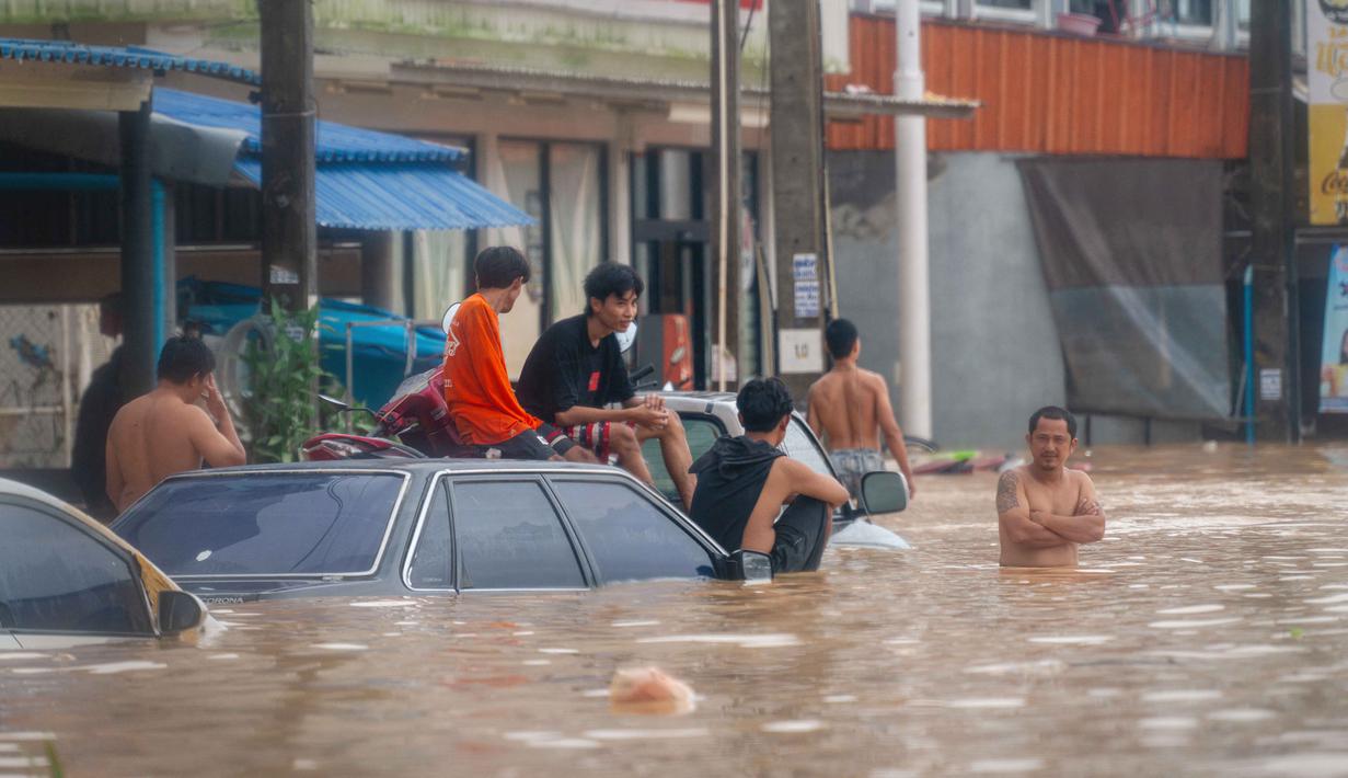 Keadaan darurat dan peringatan baru untuk hujan lebat dan banjir bandang telah dikeluarkan oleh Departemen Meteorologi Thailand. Tampak dalam foto, orang-orang berkumpul di samping sebuah toko swalayan 7/11 saat banjir tinggi melanda Hat Yai, Provinsi Songkhla, Thailand selatan, pada 26 November 2025. (Arnun Chonmahatrakool/THAI NEWS PIX/AFP)