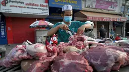 Seorang pedagang menyiapkan daging untuk dijual di sepanjang jalan karena pasar tetap tutup di tengah pembatasan lockdown yang diberlakukan untuk mencoba menghentikan lonjakan kasus virus corona COVID-19 di Phnom Penh, Kamboja, Selasa (11/5/2021). (TANG CHHIN Sothy/AFP)