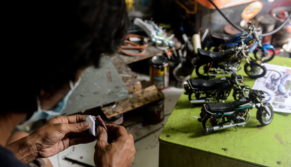 Pekerja menyiapkan salah satu bagian dari miniatur sepeda motor di bengkel kerjanya di Kelurahan Serua, Tangerang Selatan, Banten (10/10/2020). Di sana, miniatur sepeda motor yang terbuat dari bahan-bahan daur ulang dijual kepada pelanggan sebagai hadiah atau hiasan. (Xinhua/Agung Kuncahya B.)