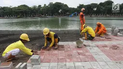 Petugas memasang konblok di pinggir Danau Sunter, Jakarta Utara, Senin (19/2). Menurut rencana, Festival Danau Sunter akan dimeriahkan sejumlah atraksi dari berbagai komunitas olahraga air seperti ski, renang, dan dayung. (Liputan6.com/Arya Manggala)