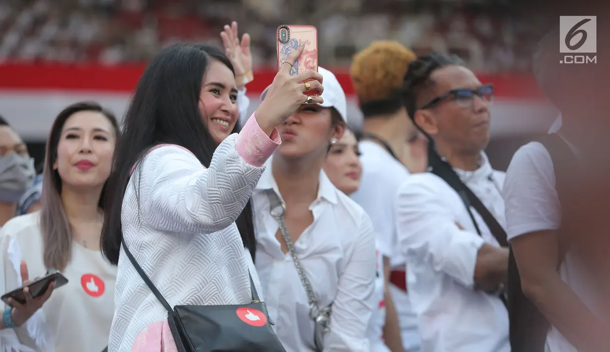 Artis Ayushita berselfie saat saat menghadiri kampanye akbar pasangan Capres dan Cawapres nomor urut 01, Jokowi - Ma'ruf Amin bertajuk 'Konser Putih Bersatu di Stadion Gelora Bung Karno (SGBK), Jakarta, Sabtu (13/4). (Kapanlagi.com/Budi Santoso)