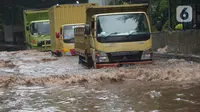 Sejumlah truk melewati banjir yang merendam terowongan di Cawang, Jakarta, Jumat (19/2/2021). Hujan yang turun sejak semalam membuat sejumlah jalanan di Ibu Kota tergenang banjir dengan ketinggian sekitar 30-50 cm. (merdeka.com/Imam Buhori)