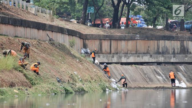 Petugas PPSU dan Sudin Tata Air Jakarta Timur membersihkan sampah dan tanaman liar di sepanjang aliran Kanal Banjir Timur (KBT), Senin (15/10). Banyak sampah yang bermunculan ke permukaan akibat debit air surut. (Merdeka.com/ Iqbal S. Nugroho)