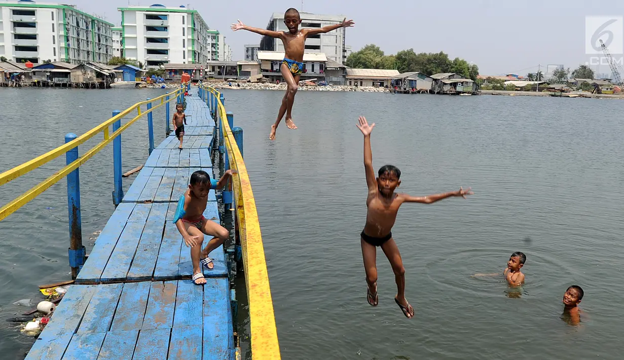 Sejumlah anak melompat saat bermain air dekat tanggul laut Muara Baru di Penjaringan, Jakarta Utara, Minggu (1/9/2019). Anak-anak memanfaatkan sisi tanggul laut raksasa (giant sea wall) sebagai   tempat  bermain alternatif. (merdeka.com/Arie Basuki)