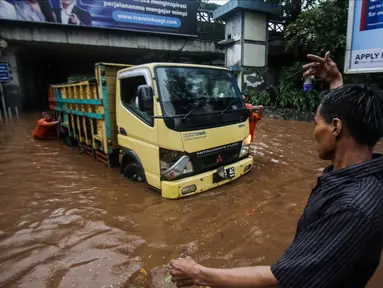 Petugas dibantu warga mendorong truk yang mogok akibat terjebak banjir di terowongan Dukuh Atas, Jakarta, Senin (11/12). Hujan lebat yang mengguyur ibu kota mengakibatkan genangan hingga satu meter di lokasi tersebut. (Liputan6.com/Faizal Fanani)