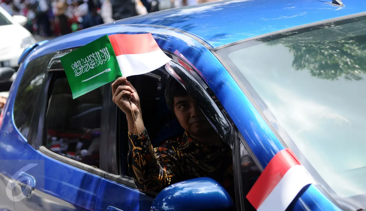 Warga mengibarkan bendera kedua negara dari dalam mobil untuk menyambut kedatangan Raja Salman bin Abdulaziz di Istana Bogor, Rabu (1/3). 21 dentuman meriam dan kibaran bendera kedua negara mewarnai sambut Raja Salman. (Liputan6.com/Helmi Fithriansyah)