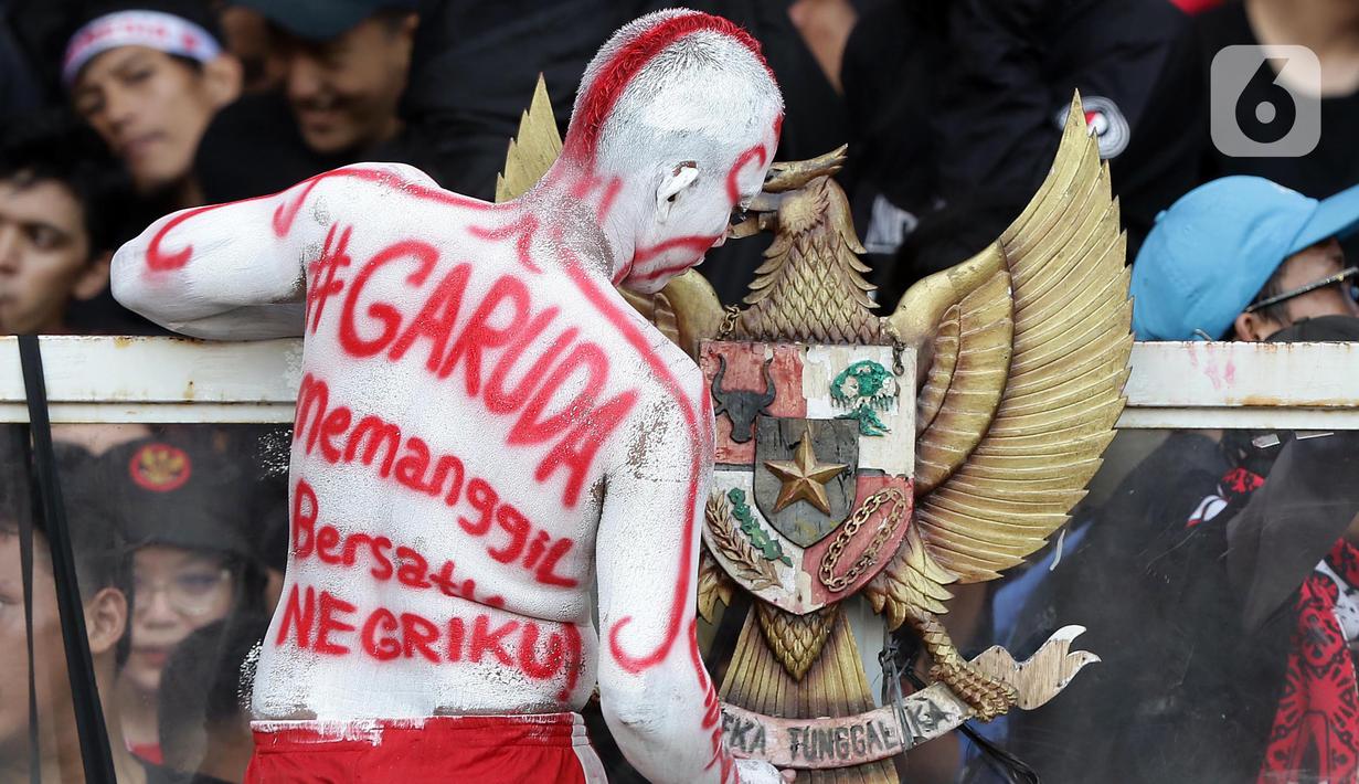 Suporter tim garuda memasang lambang negara Indonesia saat menyaksikan laga timnas Indonesia melawan Vietnam pada semifinal leg pertama Piala AFF 2022 di Stadion Utama Gelora Bung Karno, Jakarta, Jumat (6/1/2023). Indonesia akan melakoni laga tandang semifinal Piala AFF 2022 melawan Vietnam pada Senin (9/1). (Liputan6.com/Helmi Fithriansyah)
