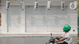 Pengendara motor melintas di depan pertokoan yang tutup di kawasan little Tokyo, Blok M, Jakarta, Rabu (21/7/2021). Pemerintah resmi menetapkan pemberlakuan pembatasan kegiatan masyarakat (PPKM) level 4 hingga 25 Juli mendatang untuk mencegah penyebaran virus Covid-19. (Liputan6.comn/Faizal Fanani)
