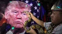 Seorang dukun melakukan ritual mistik memegang ular di depan gambar Presiden AS Donald Trump, di dalam sebuah apartemen di Lima, Peru, Rabu (16/9/2020). Para dukun berkumpul untuk memprediksi siapa pemenang dari pemilihan presiden AS yang akan dihelat pada 3 November mendatang (AP Photo/Rodrigo Abd)