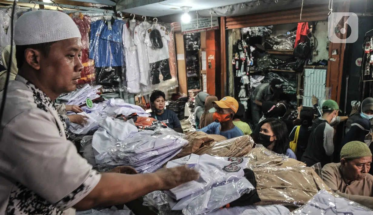 Pedagang melayani pembeli seragam sekolah di Pasar Mester Jatinegara, Jakarta Timur, Senin (3/1/2022). Salah satu pedagang mengungkapkan penjualan seragam sekolah mengalami peningkatan 50 persen seiring pemberlakuan PTM di Jakarta yang kembali digelar 100 persen. (merdeka.com/Iqbal S. Nugroho)