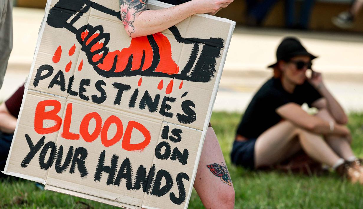 Seorang demonstran dengan membawa papan tanda bergabung dengan yang lain di luar gedung Parlemen menjelang pertemuan antara Perdana Menteri Australia Anthony Albanese dan Presiden Israel Isaac Herzog di Canberra pada Rabu 11 Februari 2026. Kunjungan resmi Presiden Israel, Isaac Herzog, ke Australia memicu gelombang unjuk rasa pro-Palestina di berbagai kota besar seperti Sydney, Melbourne, dan Canberra. (DAVID GRAY/AFP)