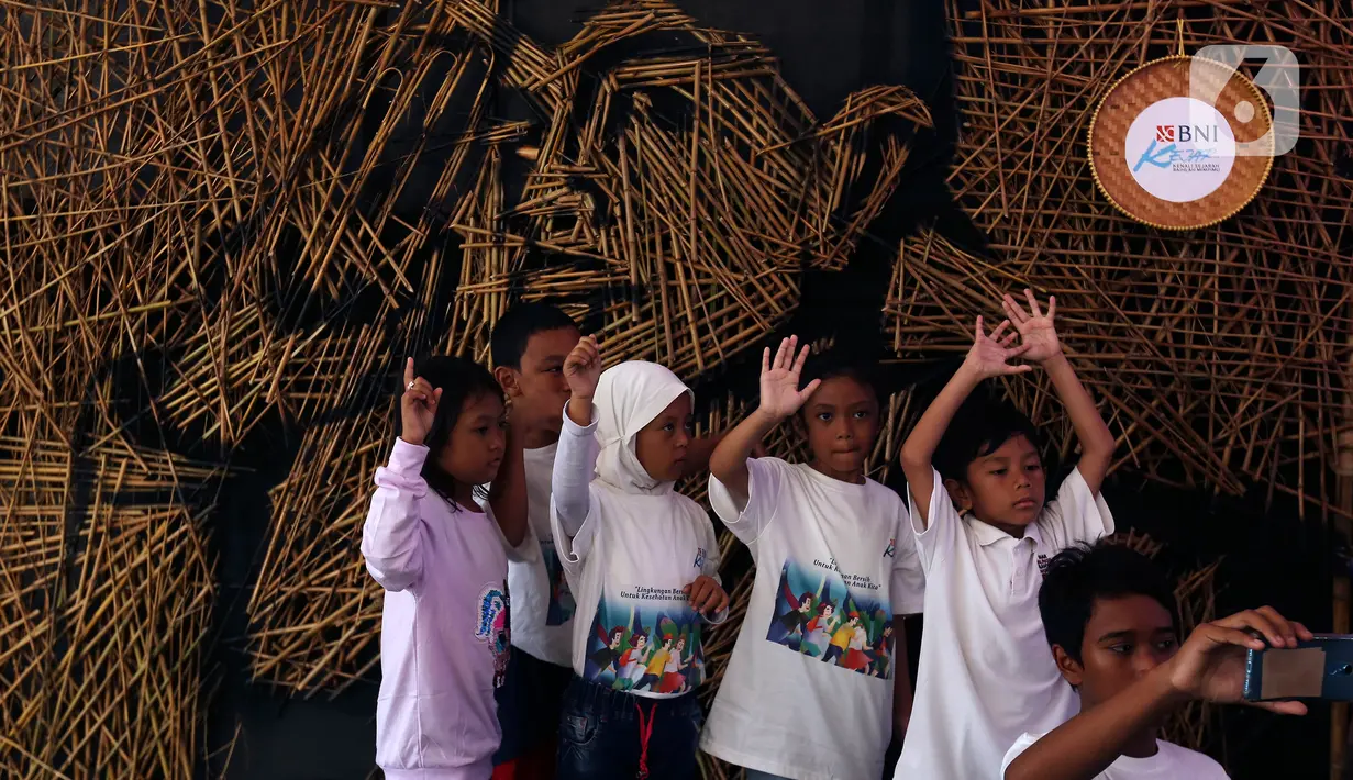 Anak-anak berfoto di depan karya instalasi bambu berbentuk wajah Jenderal Sudirman karya Nus Salomo yang dipamerkan pada Aksi BNI KEJAR atau Kenali Sejarah Raihlah Mimpimu di Terowongan Dukuh Atas, Jakarta, Minggu (24/11/2019). (Liputan6.com/Johan Tallo)