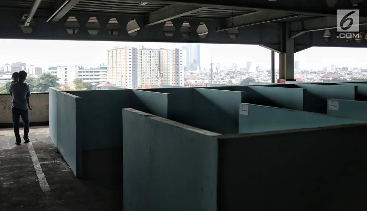Seorang pria menggendong anak dekat kios penampungan pedagang kaki lima (PKL) di Blok F Tanah Abang, Jakarta, Kamis (31/1). Hingga kini tempat untuk PKL yang tidak memperoleh lapak di skybridge Tanah Abang itu tak diminati. (Liputan6.com/Faizal Fanani)