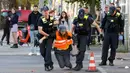 Polisi membawa seorang aktivis iklim yang memiliki sepotong permukaan jalan di tangannya usai menempelkan dirinya ke jalan untuk menarik perhatian pada aksi keadaan darurat iklim, pada tanggal 18 September 2023 di Berlin. (Odd ANDERSEN/AFP)