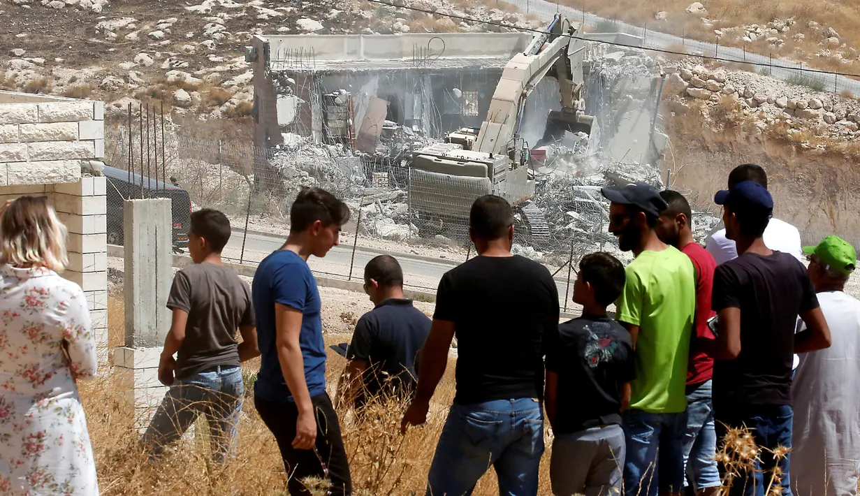 Warga Palestina menyaksikan pasukan Israel menghancurkan bangunan palestina di Yerusalem (22/7/2019).Penghancuran terkait putusan pengadilan tinggi Israel pada Juni 2019 lalu yang menolak petisi warga Palestina yang meminta pembatalan perintah militer melarang konstruksi. (AFP Photo/Ahmad Gharabli)