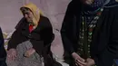 Warga lanjut usia menunggu saat yang lain mengambil makanan dan pakaian yang dikirim dari belakang truk di Samandag, selatan Hatay pada 16 Februari 2023, sepuluh hari setelah gempa berkekuatan 7,8 melanda wilayah perbatasan Turki dan Suriah. Lusinan tangan dengan panik meraih pemanas dan selimut yang dibagikan oleh donor swasta, menggambarkan keputusasaan dan kemarahan yang mencengkeram wilayah Turki 11 hari setelah bencana gempa. (Photo by Yasin AKGUL / AFP)