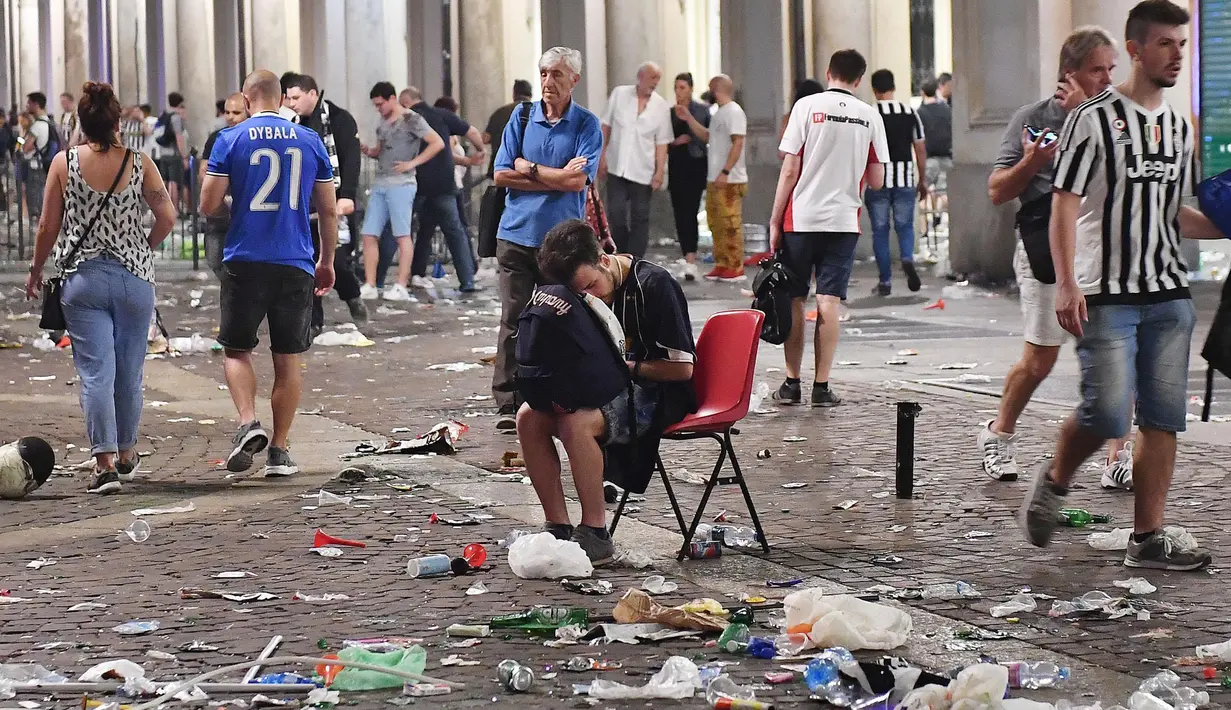 Suporter Juventus meninggalkan lokasi nonton bareng (nobar) final Liga Champions di Turin, Italia, Minggu (4/6). Ratusan orang luka-luka karena panik akibat suara ledakan beberapa saat usai final Liga Champions berakhir. (Alessandro Di Marco/ANSA via AP)