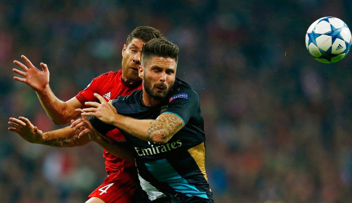 Penyerang Arsenal, Oliver Giroud berebut bola udara dengan gelandang Bayern Muenchen, Xabi Alonso pada lanjutan Grup F liga champions di stadion Allianz Arena, Munich, Jerman (4/11). Muenchen menang atas Arsenal dengan skor 5-1. (Reuters/Michael Dalder) 