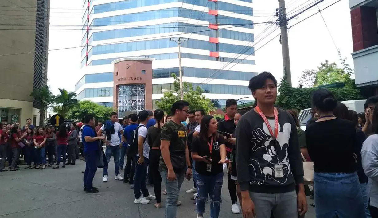 Pegawai kantor berkumpul di luar gedung setelah gempa bumi dahsyat  di Kota Davao, Filipina (29/10/2019). Gempa bumi berkekuatan M 6,8 mengguncang selatan Filipina, Selasa (29/10/2019) pagi waktu setempat. (AP Photo)