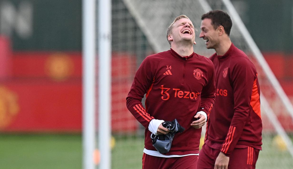 Pemain Manchester United, Donny van de Beek dan Jonny Evans, tertawa lepas saat sesi latihan di Carrington Training Complex, Senin (23/10/2023). Skuad Setan Merah tampak lepas saat sesi latihan kali ini. (AFP/Paul Ellis)