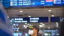 Pelancong berdiri di bawah papan informasi yang menunjukkan penerbangan dari Wuhan telah dibatalkan di Bandara Internasional Ibu Kota Beijing pada Kamis (23/1/2020). China menangguhkan semua transportasi dari dan ke kota Wuhan, yang merupakan pusat penyebaran virus korona. (AP/Mark Schiefelbein)